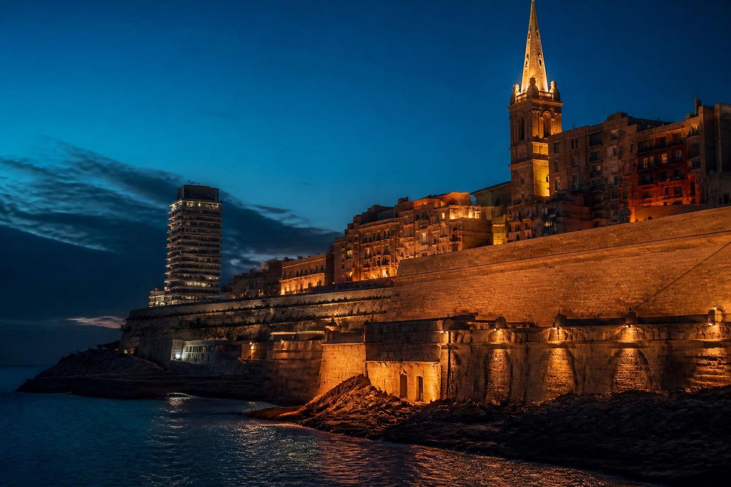 Valletta's fortification walls and seafront at blue hour, lit from the side